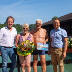 Erster Bürgermeister Florian Schneider und Bäderleiter Stefan Sajdak überreichen dem Ehepaar Hausperger Blumen und Saisonkarten für das nächste Jahr am Wöhrsee. Fotocredit: Stadt Burghausen