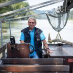 Sepp Kramler lenkt als neu ausgebildeter Plättenfahrer die Plätte „Burghausen“ sicher auf der Salzach. Fotocredit: Burghauser Touristik/Andrea Obele